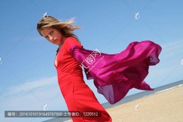 海灘上的年輕女子帶著紅色飄動的圍巾