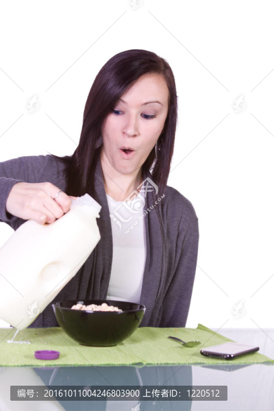 漂亮的女孩把牛奶倒在麥片粥上