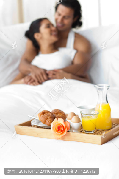 微笑的戀人在床上吃早餐
