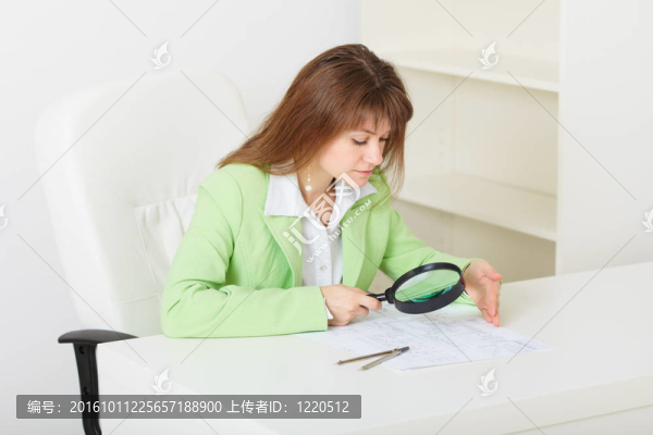 年輕的女孩坐在大桌子手中的放大鏡