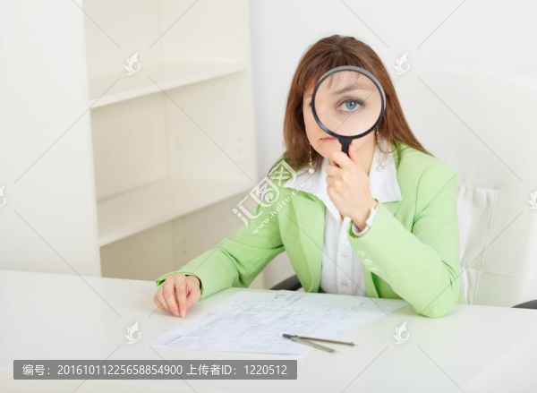 年輕的婦女坐在大桌子手中的放大鏡