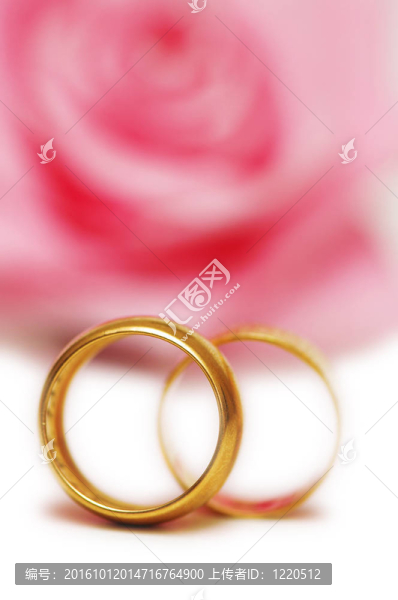 兩個(gè)結(jié)婚戒指和粉紅色的玫瑰在后臺(tái)