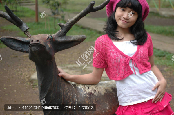 可愛(ài)的女孩站在鹿雕像旁邊