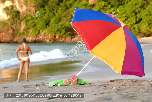 五顏六色的傘熱帶海灘的場景；沙灘巾和白色比基尼的女人