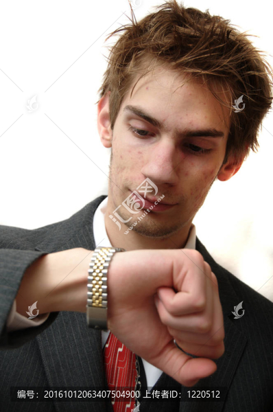 迷人的年輕商人在西裝檢查他的黃金手表的時間