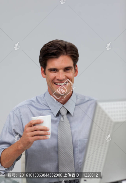 快活的商人手里拿著一個(gè)水杯坐在桌旁