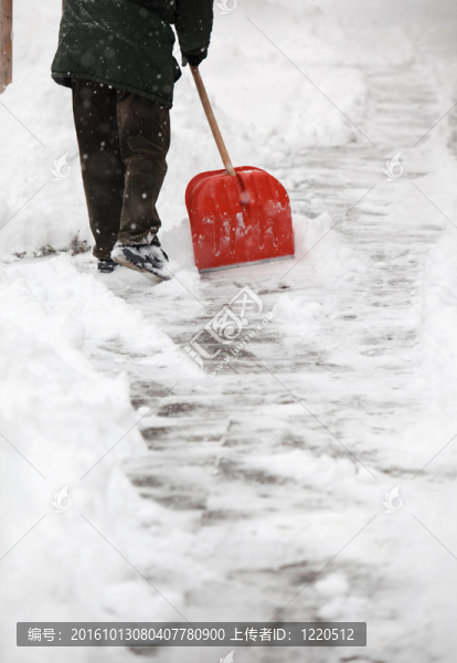 男人鏟人行道上的雪在他的房子前面的一個(gè)城市，大雪之后