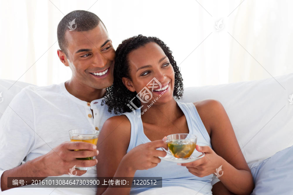 幸福的夫婦在床上喝著一杯茶