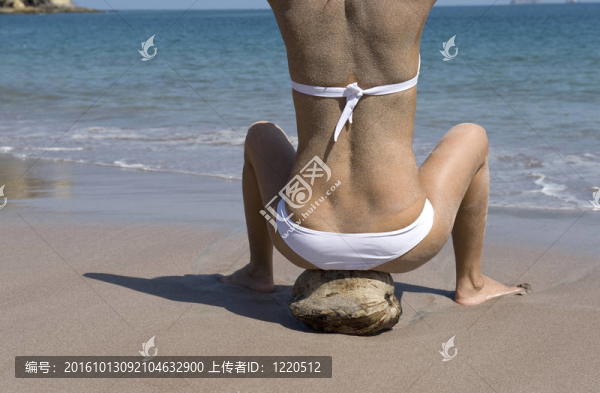 美麗的小姐在比基尼坐在熱帶海灘的椰子