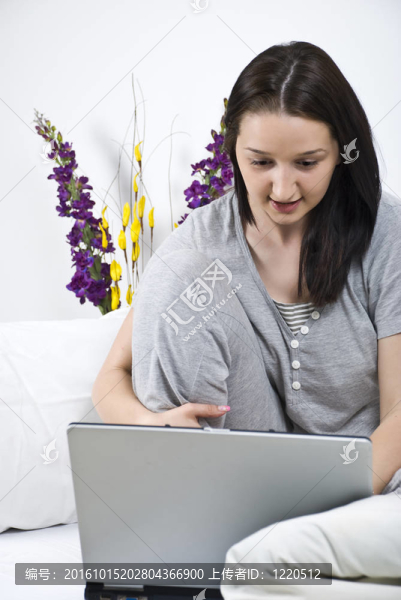 年輕的女人在床上使用筆記本電腦