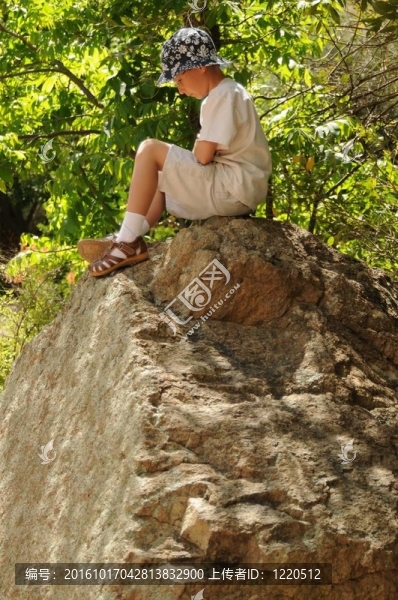獨(dú)自坐在一塊大石頭上的男孩