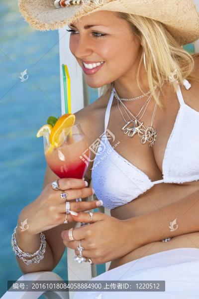 在海邊比基尼喝雞尾酒的年輕漂亮的女人