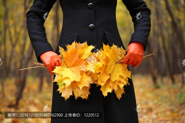 女性手戴紅色手套，黃色葉子