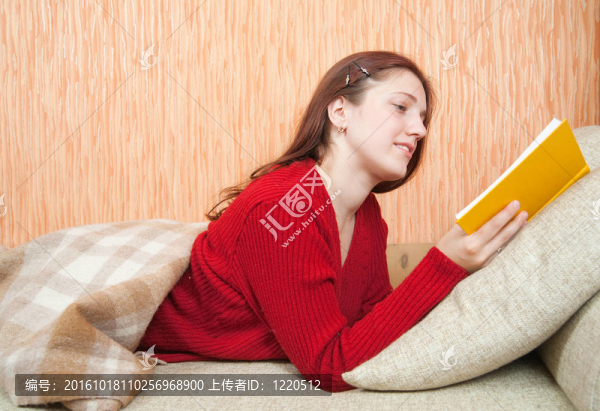 漂亮的年輕女孩在沙發(fā)上看書(shū)