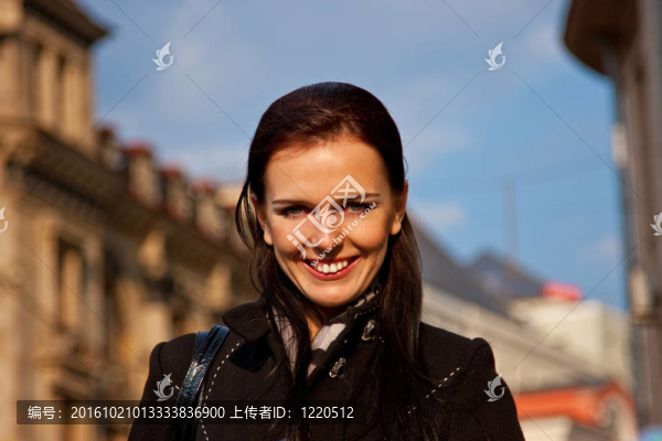 微笑的女孩在黑色外套在城市