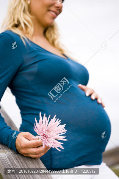抱粉紅色花孕婦的側(cè)面圖
