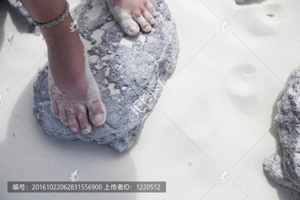 站在海灘巖石上的女孩的腳