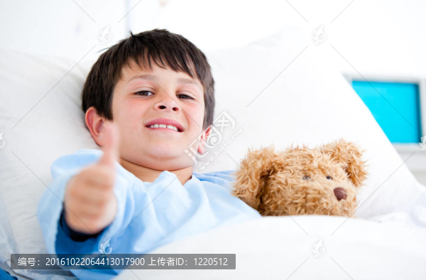 在醫(yī)院病床上抱著泰迪熊的小男孩
