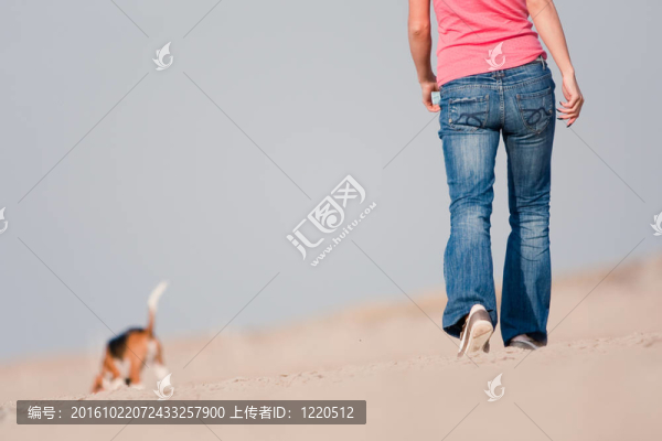 在海灘上遛狗的年輕女子