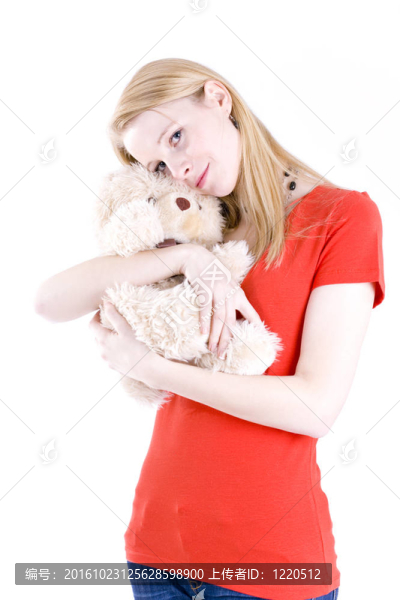 在紅房子擁抱泰迪的年輕的金發(fā)女人