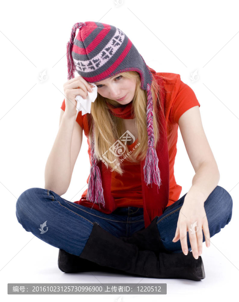 穿著交叉腿的年輕女子坐在地板上，在冬天拿著手帕