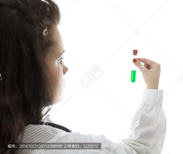 年輕的女醫(yī)生用聽診器保持綠色液體的小瓶