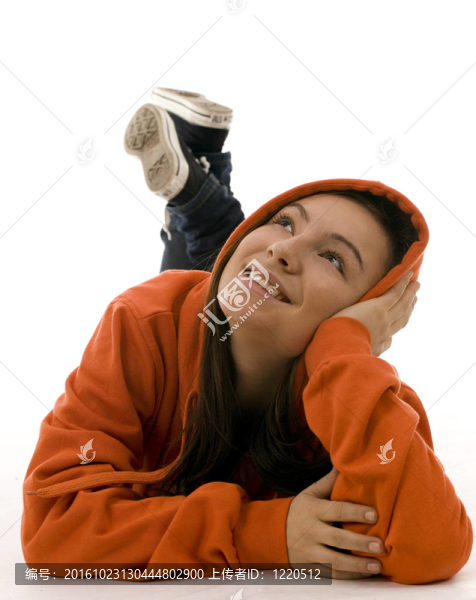 躺在地板上的橙色運動衫罩的女孩微笑；靠在手掌頭
