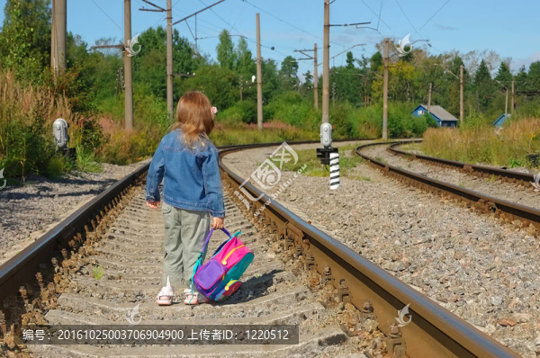 在鐵路鐵軌上帶著背包的小女孩