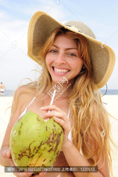 口渴的女人在海灘上喝椰子水