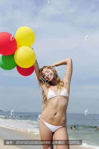 海灘上拿著五顏六色的氣球的女人