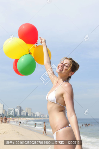 海灘上拿著五顏六色的氣球的女人
