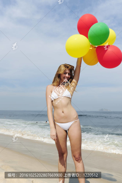海灘上拿著五顏六色的氣球的女人