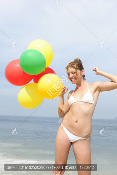 海灘上拿著五顏六色的氣球的女人