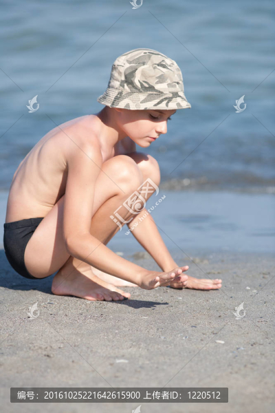 在海灘上玩帽子的小男孩