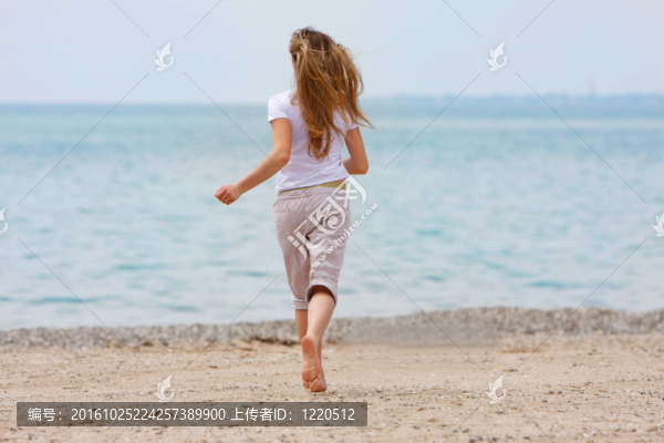 年輕的女孩在海灘上逃跑