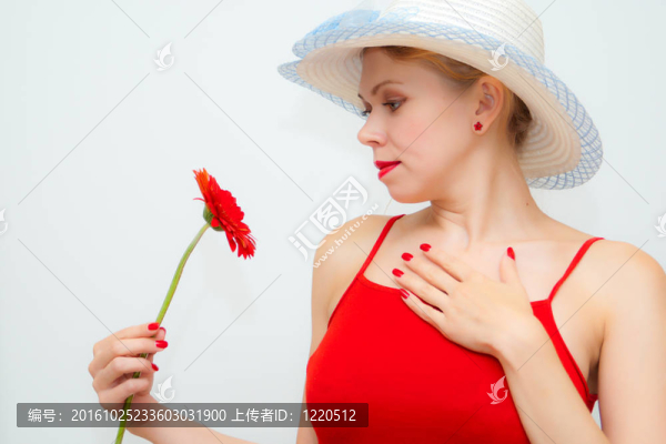 漂亮的女孩看著一朵紅色的花