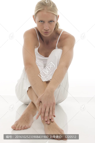 一個(gè)穿著白色衣服的年輕白人婦女坐在地板上