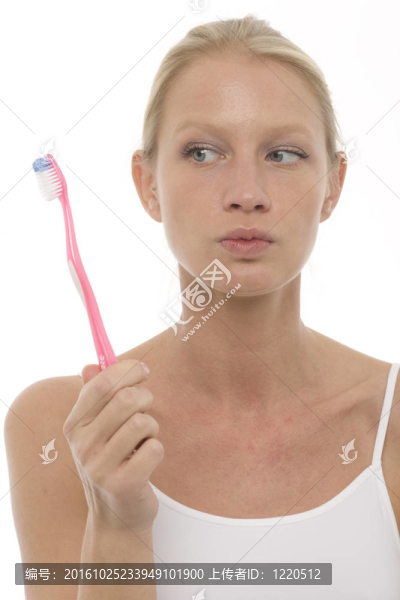 一個年輕美麗的白人女子閉上嘴拿著一把牙刷，肖像
