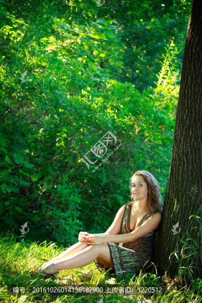 美麗的女人坐在旁邊的樹