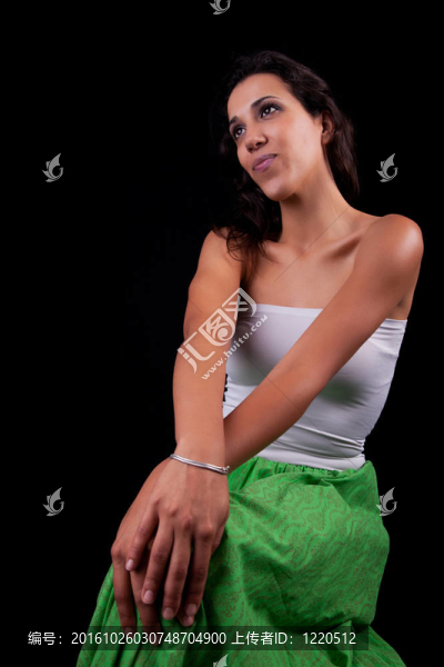 年輕漂亮的女人坐著沉思的；孤立的黑色背景