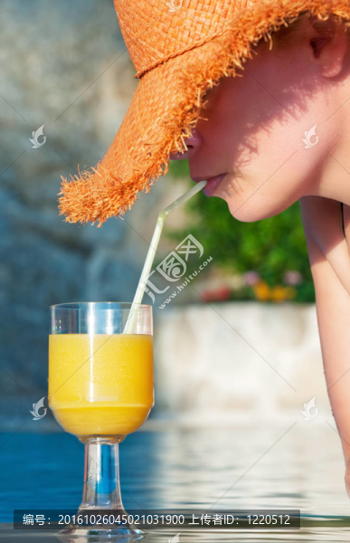 迷人的年輕女子在泳池里享受清涼的飲料