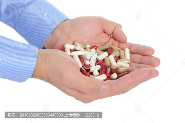 在男性手中的紅色和白色的藥片
