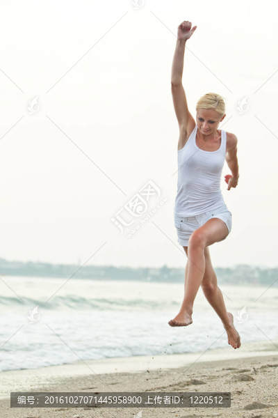 快樂的年輕女子在海灘上跳