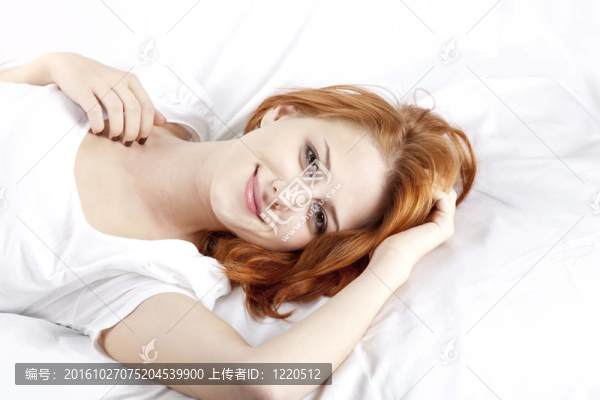 漂亮的紅頭發(fā)的睡在白色的睡衣躺在床上的女人