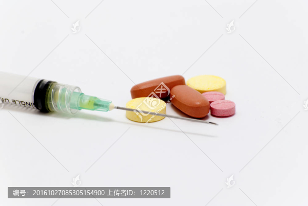白色背景上的注射器和藥丸