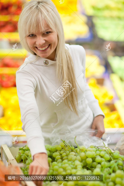 美麗的年輕女人買水果和蔬菜