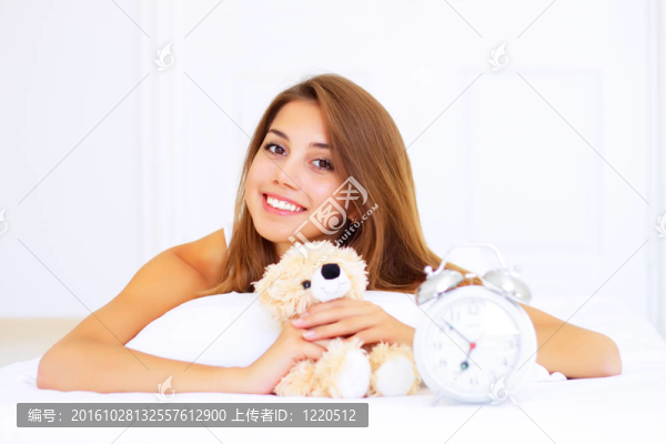 微笑的女孩躺在床上泰迪熊