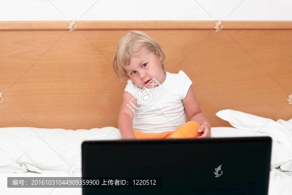 一個小孩坐在床上，看著屏幕