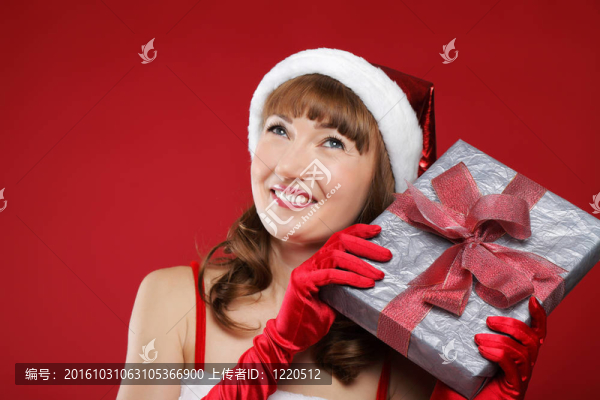 年輕漂亮的女孩裝扮成圣誕老人手里拿著禮物。