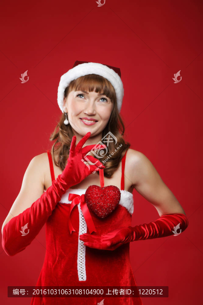 年輕迷人的女孩裝扮成圣誕老人，手里拿著一份禮物。